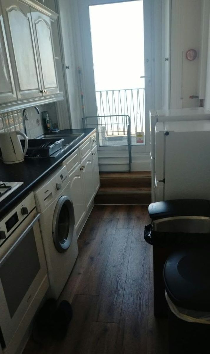 Clean galley kitchen with wiped worktops and mopped wooden floor